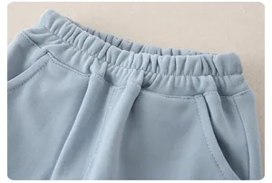 Detail of light blue baby trousers featuring elastic waist and reinforced stitching