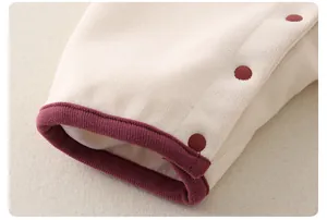 Détail de la manche d'une grenouillère avec poignet bord-côte bordeaux et boutons-pression