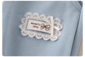 Macro detail of baby clothing showing lace trim, ribbon bow, and Wonderful candy print
