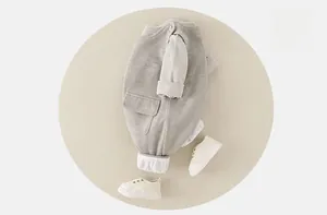 Detailed top view of soft grey knit cotton baby bodysuit with cream infant shoes