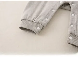 Close-up of baby romper ribbed cuffs and white snap button closure on grey knit fabric
