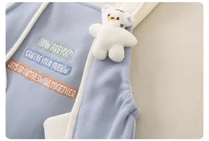 Dettaglio di abbigliamento neonato in morbida maglia con ricami e orsetto di peluche