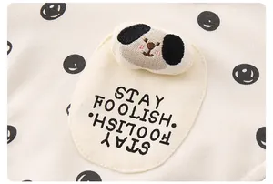 Dettaglio completo di vestiti per neonati con cane ricamato e scritta Stay Foolish