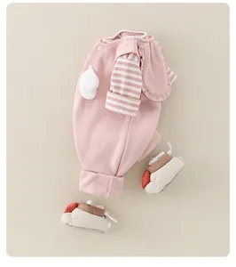 Detailed view of pink baby cotton romper with pom-poms and matching soft-sole baby shoes