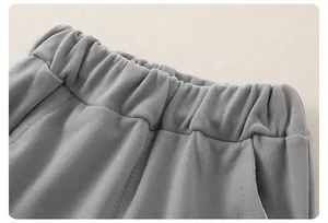 Dettaglio dei pantaloni grigi da neonato in maglia a nido d'ape con ampia fascia elastica