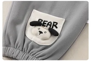 Dettaglio dei pantaloni grigi per neonati con patch animale 3D e ricamo della scritta BEAR
