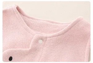 Close-up of baby light pink cotton knit jumpsuit collar with a white snap button detail