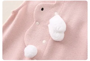 Detail of pink knitted baby vest with plush bunny patch and white button fasteners