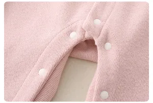 Detailed macro view of the snap-button crotch on a pink knitted baby romper suit