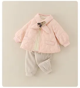 Detail van roze gewatteerd babyjasje met hartjespatroon en beige corduroy broekje