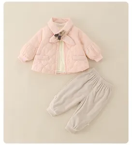 Detail van roze doorgestikt babyjack met konijnenbroche en corduroy broek in beige