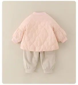 Detail van gewatteerd hartjesjack en beige corduroy broek voor baby meisjes