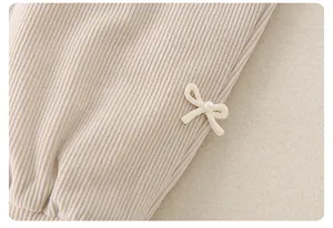 Detailopname van beige corduroy stof met een witte gebreide strik en parel