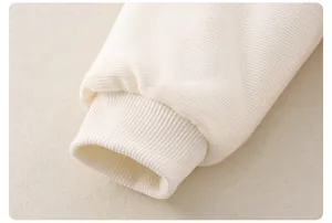 Detailed macro view of the cream ribbed cuffs and soft corduroy fabric for baby rompers