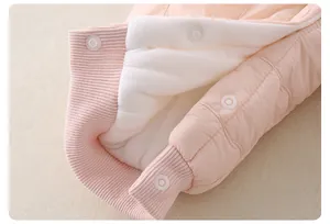 Detailed macro view of baby romper featuring pink quilted fabric and warm fleece lining