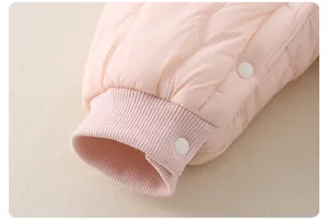 Detail of pink quilted baby bodysuit showing elastic ribbed cuffs and button closure