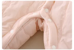 Macro shot of pink quilted baby romper fabric with white snap buttons and wavy stitching