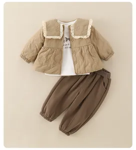 Close-up of quilted beige baby jacket with ruffled collar and matching brown trousers