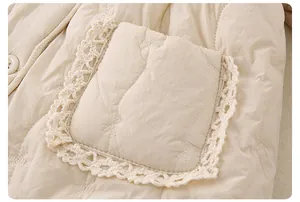 Detail of baby winter jacket showing quilted texture with floral embroidery and lace trim