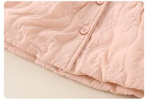 Detail of pink quilted baby jacket featuring bow embroidery and matching round resin buttons