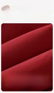 Close-up detail of soft red cotton down vest fabric showing smooth texture and high quality