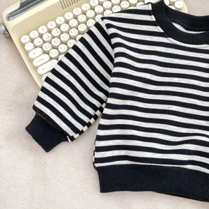 Flachbild-Detail eines gestreiften Jungen-Sweatshirts mit Rippbündchen und Retro-Schreibmaschine