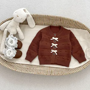 Detail der Baby-Strickjacke für Mädchen mit Texturmustern und Schleifen im Korb