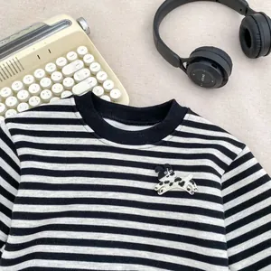 Detail eines gestreiften Jungen-Sweatshirts mit Hundestickerei auf beigem Stoff