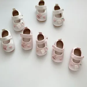 Detailansicht von weichen Baby-Seidenschuhen mit süßer Kaninchenstickerei und Schleifen