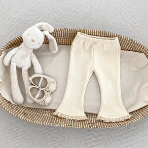 Dettaglio dei pantaloni a campana in maglia a costine per neonata con bordo in pizzo