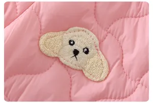 Détail d'un body matelassé rose pour bébé avec un écusson brodé chiot 3D