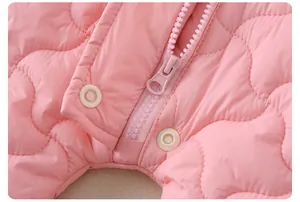 Détail de grenouillère matelassée rose avec fermeture éclair et boutons pression de sécurité