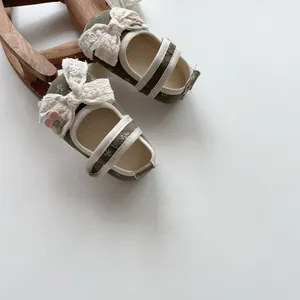 Detail of baby walking shoes with green floral fabric and pink floral lace bows