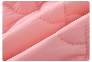 Détail macro du tissu matelassé rose avec coutures ondulées pour vêtements d'hiver de bébé