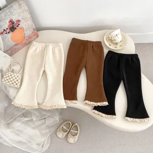 Dettaglio dei pantaloni svasati in pile per bambina con pizzo fine in tre colori neutri