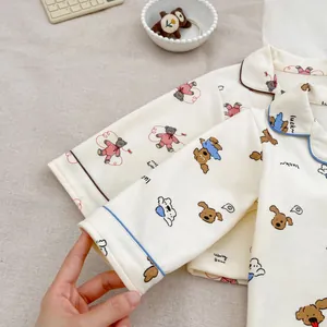 Detail of soft cotton baby pajamas featuring cute bear and puppy prints with contrast piping