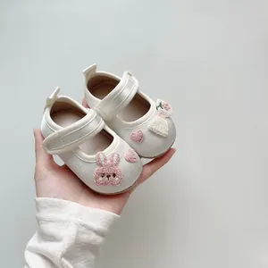 Nahaufnahme weißer Baby-Mary-Janes mit süßer Kaninchen-Stickerei und Klettverschluss