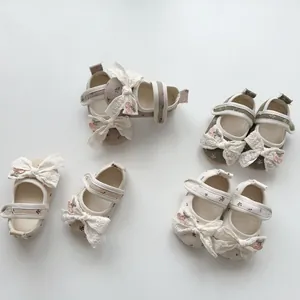 Detailed close-up of floral baby walking shoes with lace bows and velcro straps