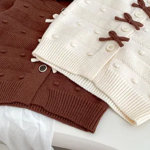 Detailansicht der gestrickten Kleinkinderjacken mit 3D-Schleifen und Texturstoffen