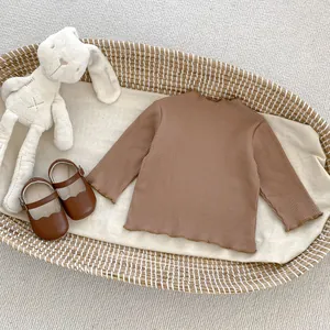 Dettaglio top neonata in cotone a coste marrone con volant e scarpe tipo Mary Jane