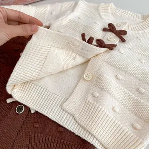 Detailansicht der Baby-Strickjacke mit brauner Schleife und weichem Quadratmuster