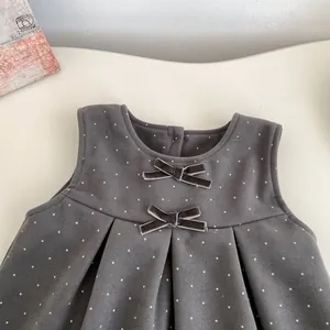 Deep grey polka dot sleeveless baby dress with velvet bows in a flat lay view