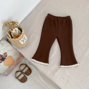 Dettaglio dei pantaloni a zampa marroni da bambina con pizzo bianco ed elastico in vita