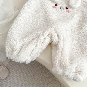 Close-up of white plush baby romper fabric featuring soft cartoon rabbit embroidery