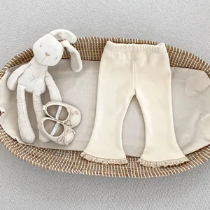 Dettaglio dei pantaloni svasati in maglia a coste beige con bordo in pizzo delicato