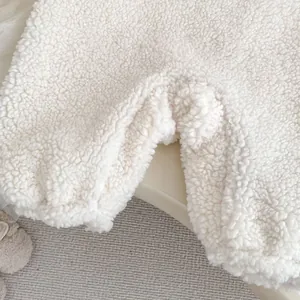 Close-up of thick white teddy fleece fabric and stitching on baby winter jumpsuit