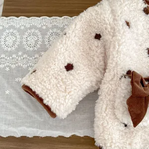 Dettaglio della giacca in pile da bambina con fiocco in velluto e trama floreale