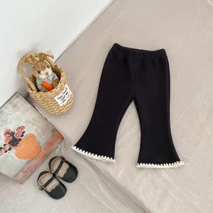 Detail of toddler black flared pants featuring delicate white crochet trim at the hemline