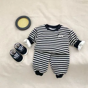 Flachbild von gestreiftem Baby-Trainingsanzug mit Stickerei und weichen Babyschuhen