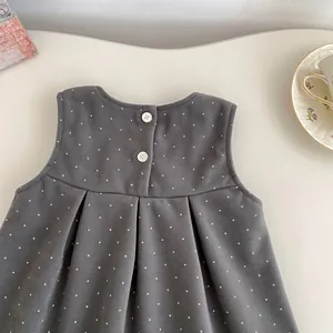 Detailed view of dark grey polka dot toddler dress with button closure and pleats